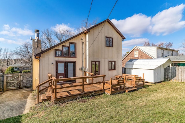 back of house with a storage shed, an outdoor structure, fence, a lawn, and a chimney