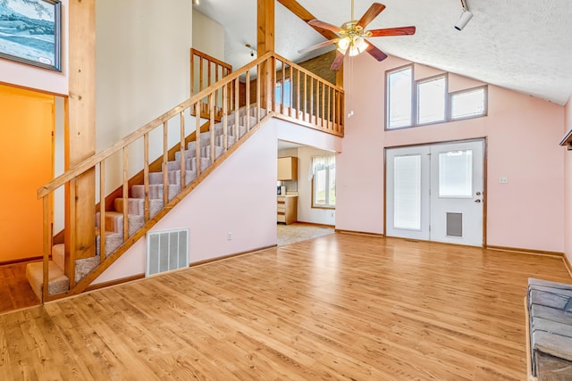 unfurnished living room featuring visible vents, ceiling fan, a textured ceiling, wood finished floors, and stairs