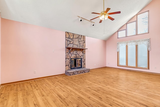 unfurnished living room featuring a stone fireplace, wood finished floors, a ceiling fan, and baseboards