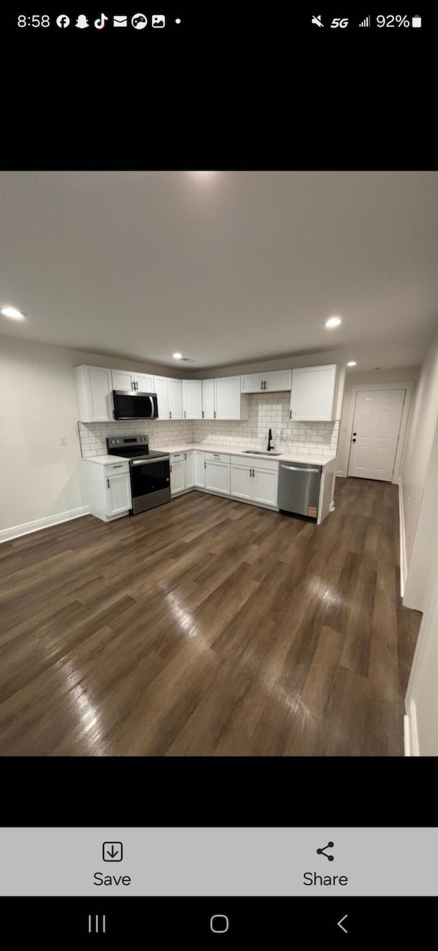 kitchen featuring stainless steel appliances, white cabinets, decorative backsplash, and dark wood-style floors