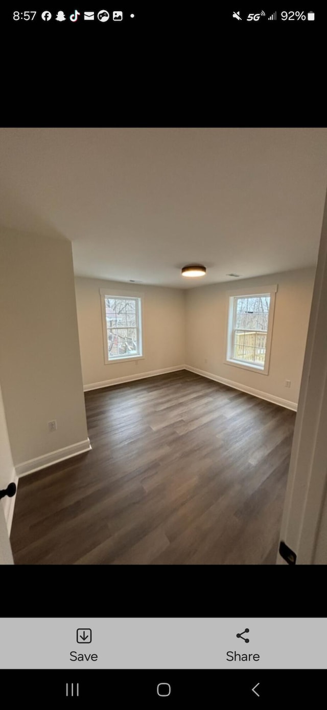 empty room with baseboards, a wealth of natural light, and wood finished floors