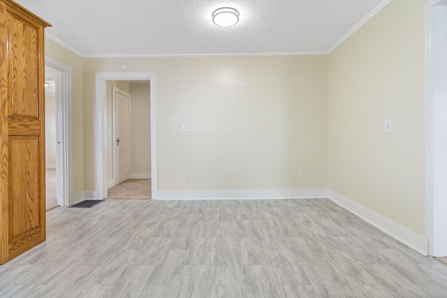 empty room with crown molding, a textured ceiling, and baseboards