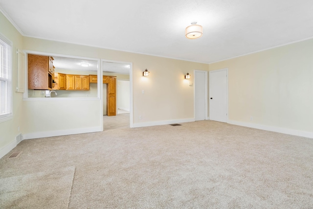 unfurnished living room with light carpet, crown molding, visible vents, and baseboards