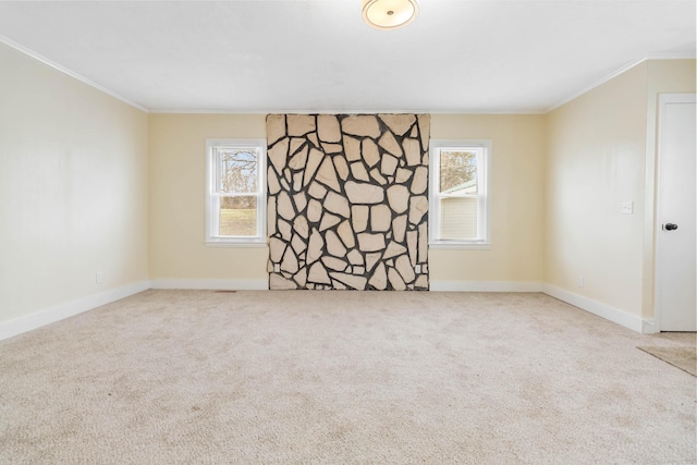 carpeted spare room featuring baseboards, a wealth of natural light, and crown molding