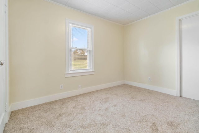 carpeted spare room with ornamental molding and baseboards