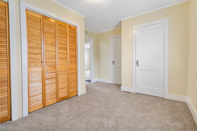 unfurnished bedroom featuring baseboards, carpet, ornamental molding, and a closet