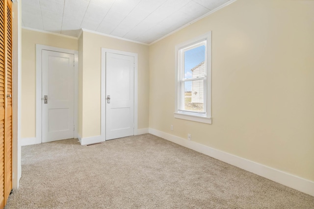 unfurnished room with baseboards, carpet floors, and crown molding