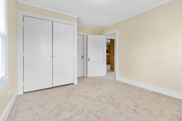 unfurnished bedroom with baseboards, a closet, ornamental molding, and carpet flooring