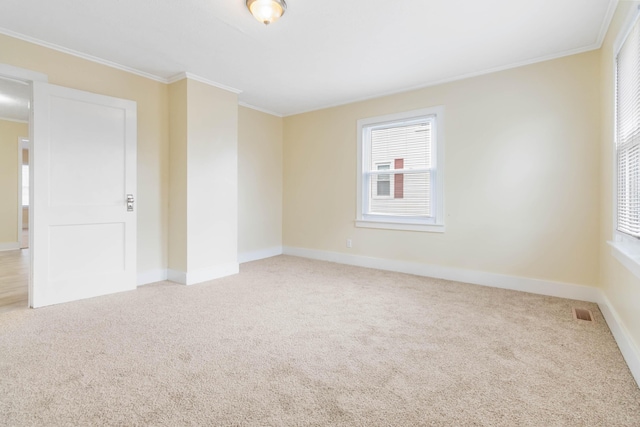 carpeted spare room with ornamental molding, visible vents, and baseboards