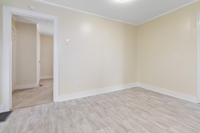 spare room with baseboards, visible vents, ornamental molding, a textured ceiling, and light wood-style floors