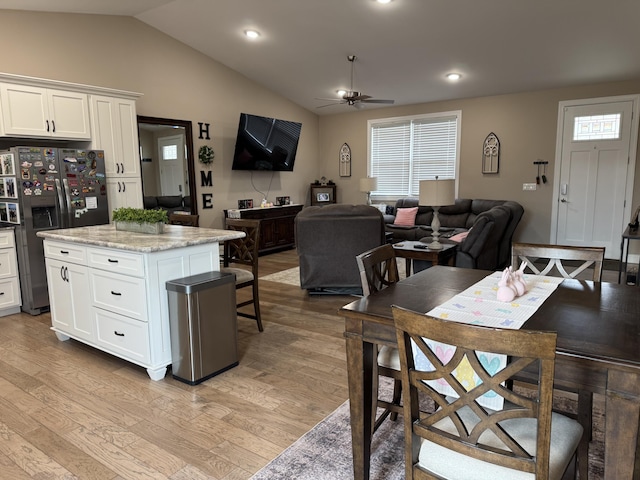 kitchen featuring white cabinets, open floor plan, vaulted ceiling, light wood-style floors, and stainless steel refrigerator with ice dispenser