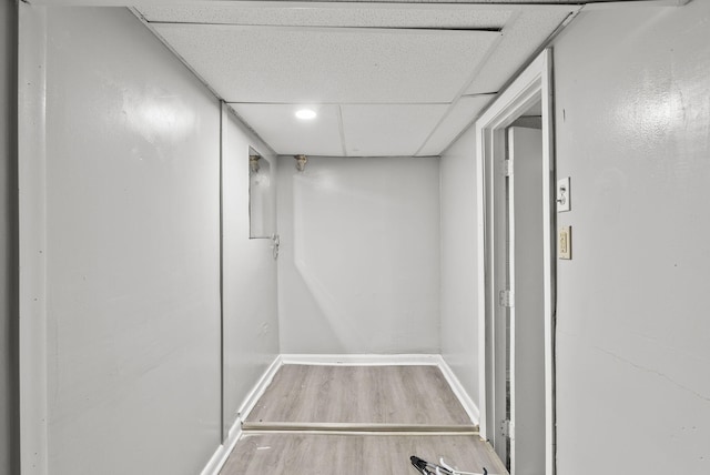 interior space with baseboards, a drop ceiling, and wood finished floors