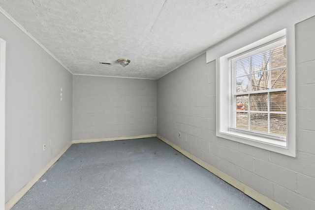 empty room with concrete block wall, visible vents, and concrete floors