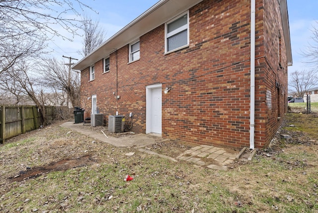 view of home's exterior with brick siding, fence, and central AC unit