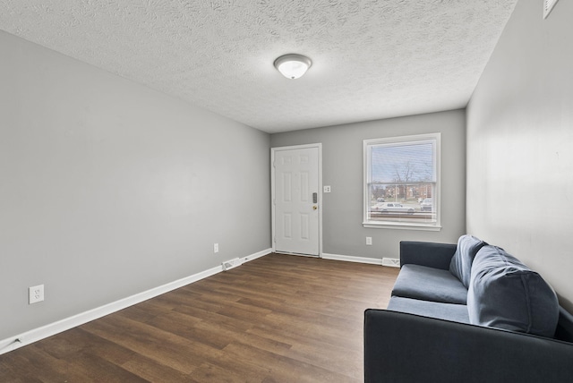 sitting room featuring dark wood-style floors, a textured ceiling, visible vents, and baseboards