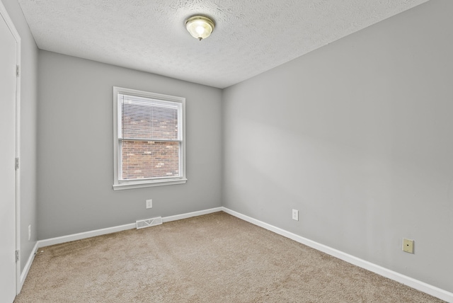 carpeted spare room featuring baseboards, visible vents, and a textured ceiling