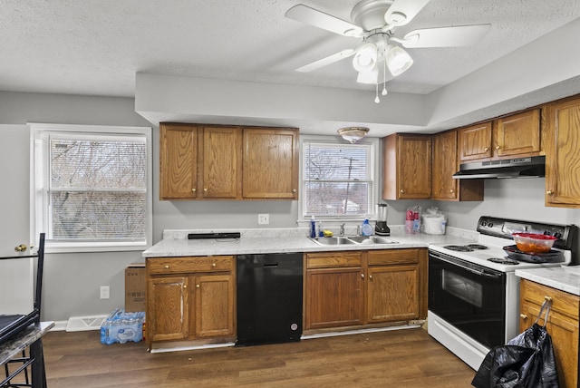 kitchen featuring electric range oven, dishwasher, brown cabinets, under cabinet range hood, and a sink