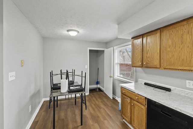 kitchen featuring a textured ceiling, baseboards, black dishwasher, brown cabinets, and dark wood finished floors