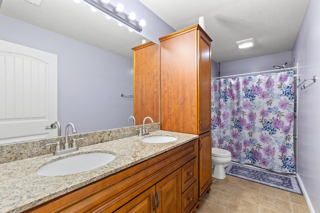 full bath with a sink, toilet, tile patterned floors, and a textured ceiling