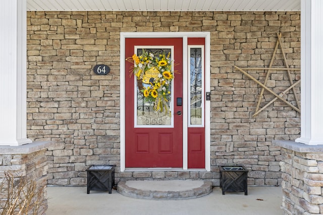 view of exterior entry featuring brick siding and stone siding