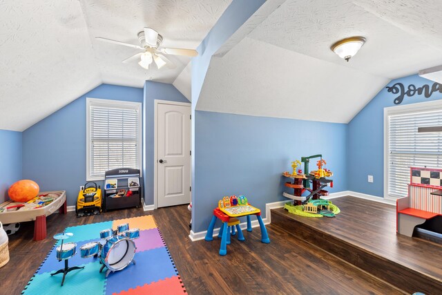 playroom featuring baseboards, a textured ceiling, wood finished floors, and vaulted ceiling