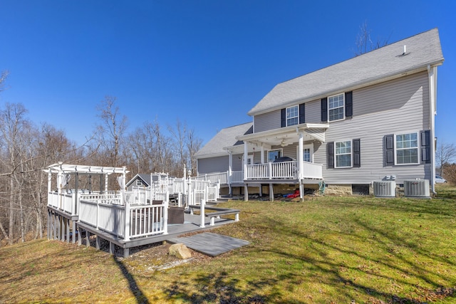 rear view of house featuring a deck, central air condition unit, a lawn, and a shingled roof