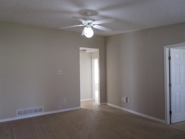 spare room with baseboards, visible vents, a ceiling fan, and light colored carpet