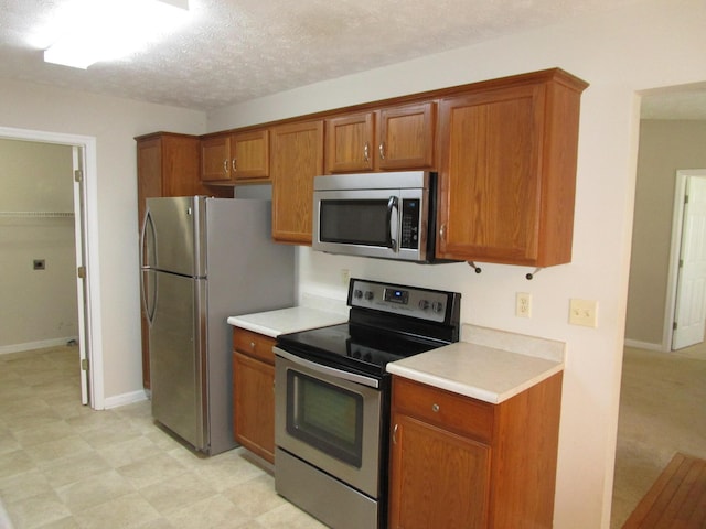 kitchen with stainless steel appliances, light countertops, and brown cabinetry