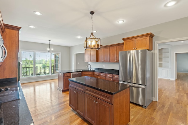 kitchen with a peninsula, light wood-style flooring, appliances with stainless steel finishes, and a sink