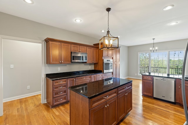 kitchen featuring a center island, a notable chandelier, hanging light fixtures, light wood-style flooring, and appliances with stainless steel finishes