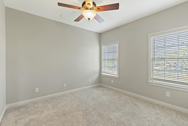 carpeted empty room featuring ceiling fan and baseboards