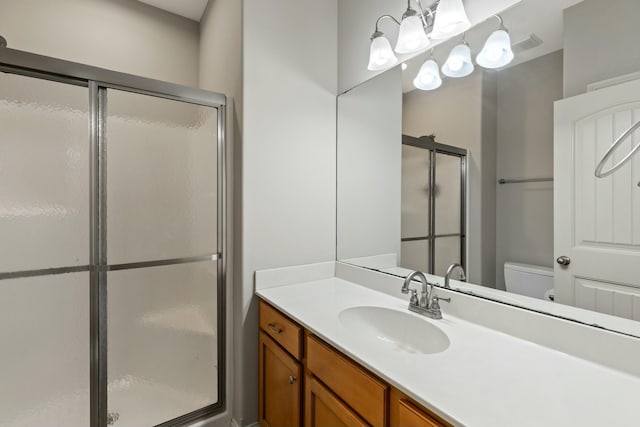 bathroom with vanity, a shower stall, and toilet