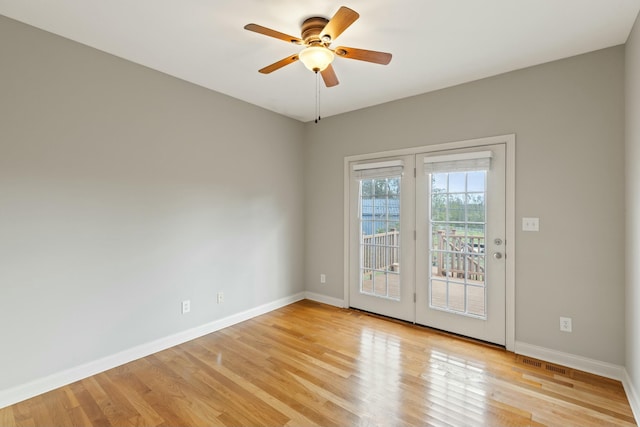 spare room featuring light wood-style floors, visible vents, baseboards, and a ceiling fan