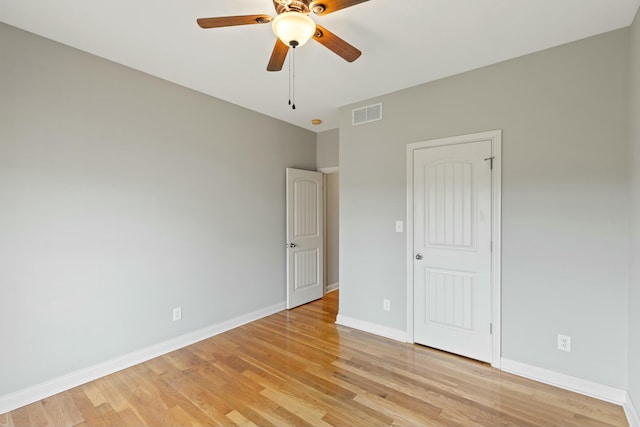 empty room featuring light wood-style floors, visible vents, ceiling fan, and baseboards