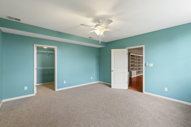 unfurnished bedroom with a spacious closet, visible vents, and baseboards