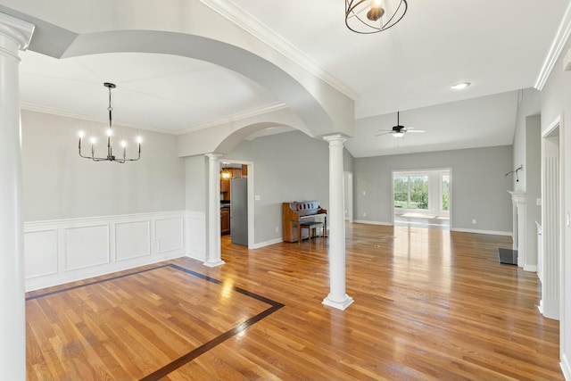 interior space featuring arched walkways, ceiling fan with notable chandelier, ornate columns, light wood finished floors, and crown molding