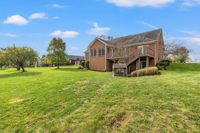 back of property featuring brick siding, a yard, a wooden deck, and stairs