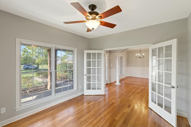 unfurnished room with french doors, a wainscoted wall, visible vents, wood finished floors, and ceiling fan with notable chandelier