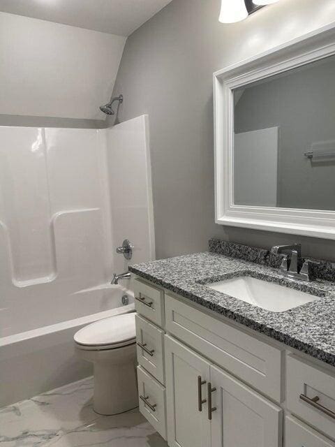 full bathroom featuring toilet, vanity, vaulted ceiling, marble finish floor, and shower / washtub combination