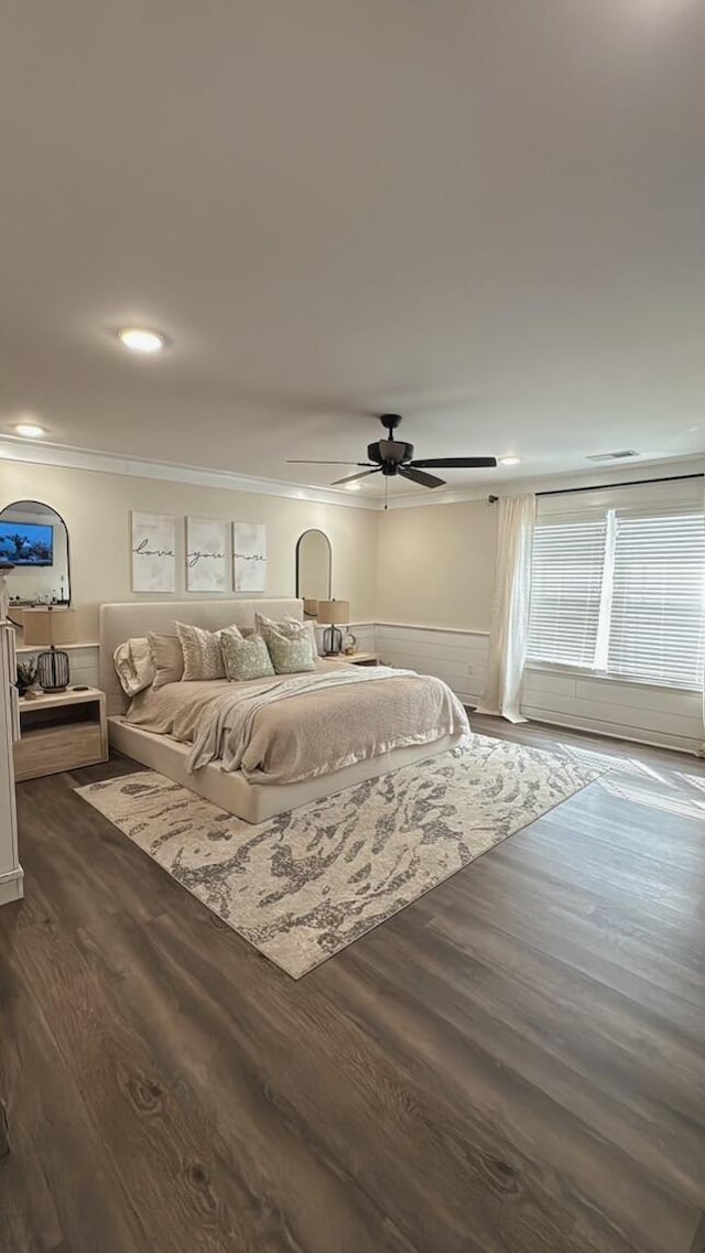 bedroom featuring a wainscoted wall, crown molding, a ceiling fan, and dark wood-style flooring