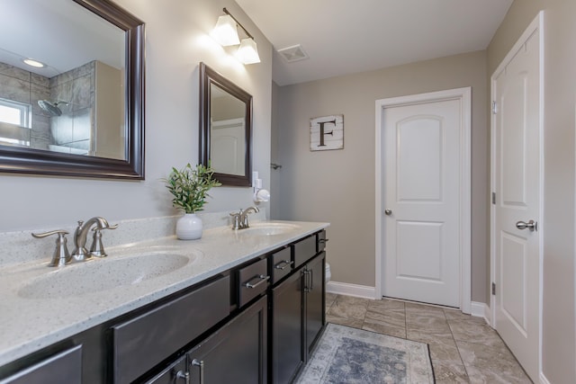 bathroom featuring visible vents, a sink, baseboards, and double vanity