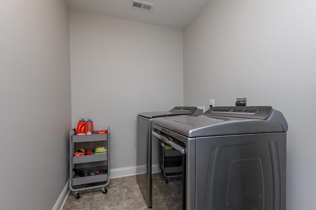 laundry area with laundry area, baseboards, visible vents, and washer and dryer