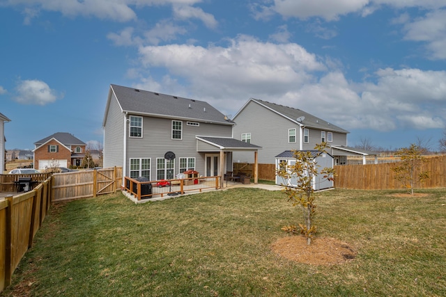 rear view of property featuring an outbuilding, a patio area, a yard, and a fenced backyard