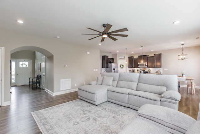 living area featuring dark wood-style floors, arched walkways, visible vents, and recessed lighting