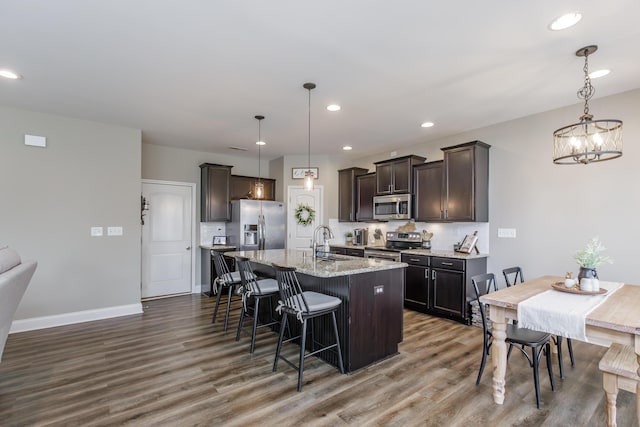 kitchen featuring dark brown cabinetry, backsplash, stainless steel appliances, and a sink