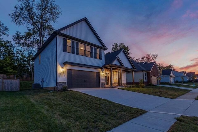 view of front of home featuring an attached garage, a front yard, fence, stone siding, and driveway