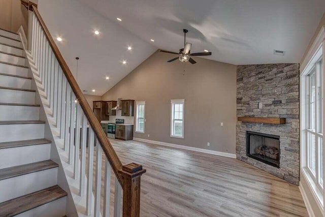 interior space with a fireplace, light wood finished floors, visible vents, stairway, and high vaulted ceiling