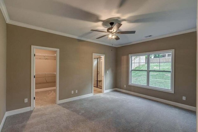 unfurnished bedroom with visible vents, crown molding, a spacious closet, and baseboards