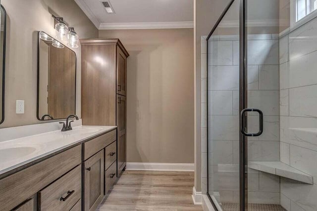 bathroom featuring a stall shower, visible vents, baseboards, crown molding, and a sink