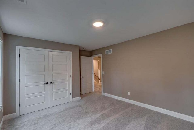 unfurnished bedroom with a closet, carpet flooring, visible vents, and baseboards